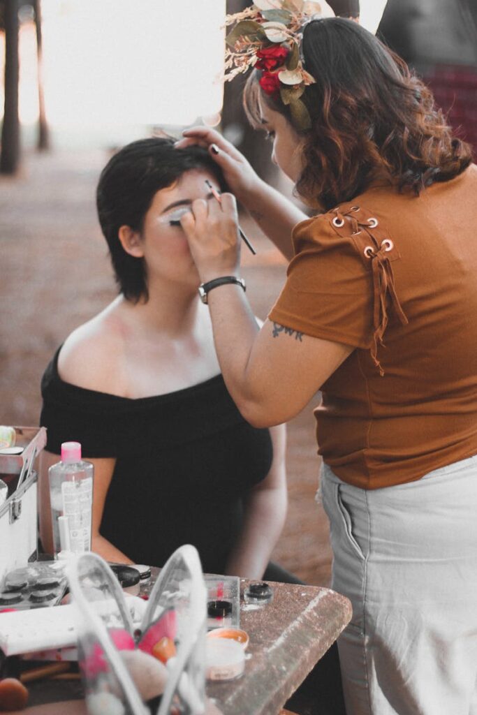 Professional makeup artist applying cosmetics to a model outdoors, preparing for a photoshoot.